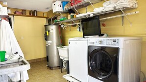 A laundry room with a washing machine, dryer, and stacked laundry on shelves. - Premium 2 Queen Bed Smoking (Sparta, GA)