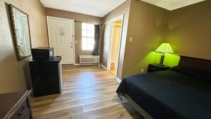 A bedroom with a bed, a dresser, a mirror, a heater, and a window with curtains. - Queen Bed | Smoking | Sparta, GA (Sparta, GA)