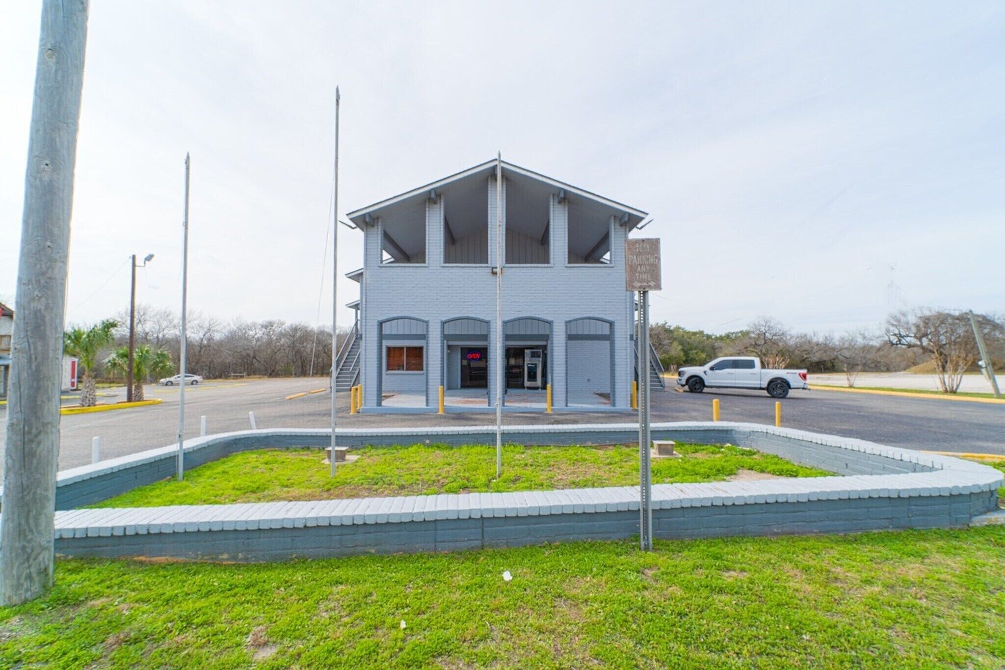 A two-story building with a flat roof and a sign indicating parking availability.