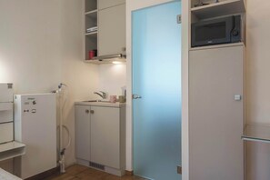 Une cuisine compacte équipée d’un four à micro-ondes, d’un réfrigérateur et d’un évier.