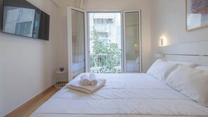 Ein Hotelzimmer mit Bett, einem kleinen Tisch mit einer Schale, einem gerahmten Bild an der Wand und einem Balkon mit Geländer.
