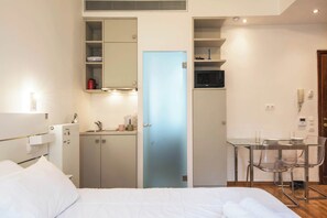 A hotel room with a bed, a desk with a chair, a microwave, and a small kitchenette area. - Syntagma Gem 2 Steps from Syntagma Square (Athina)