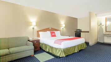 A hotel room with a bed, a green-striped sofa, a nightstand, a desk, and a mirror.