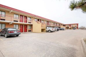 A motel with multiple floors, a central staircase, and several parked cars.