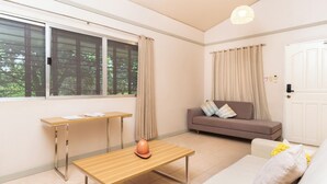A room with a sofa, a table, a vase, and a window with curtains. - The Glens Tagaytay (Tagaytay)