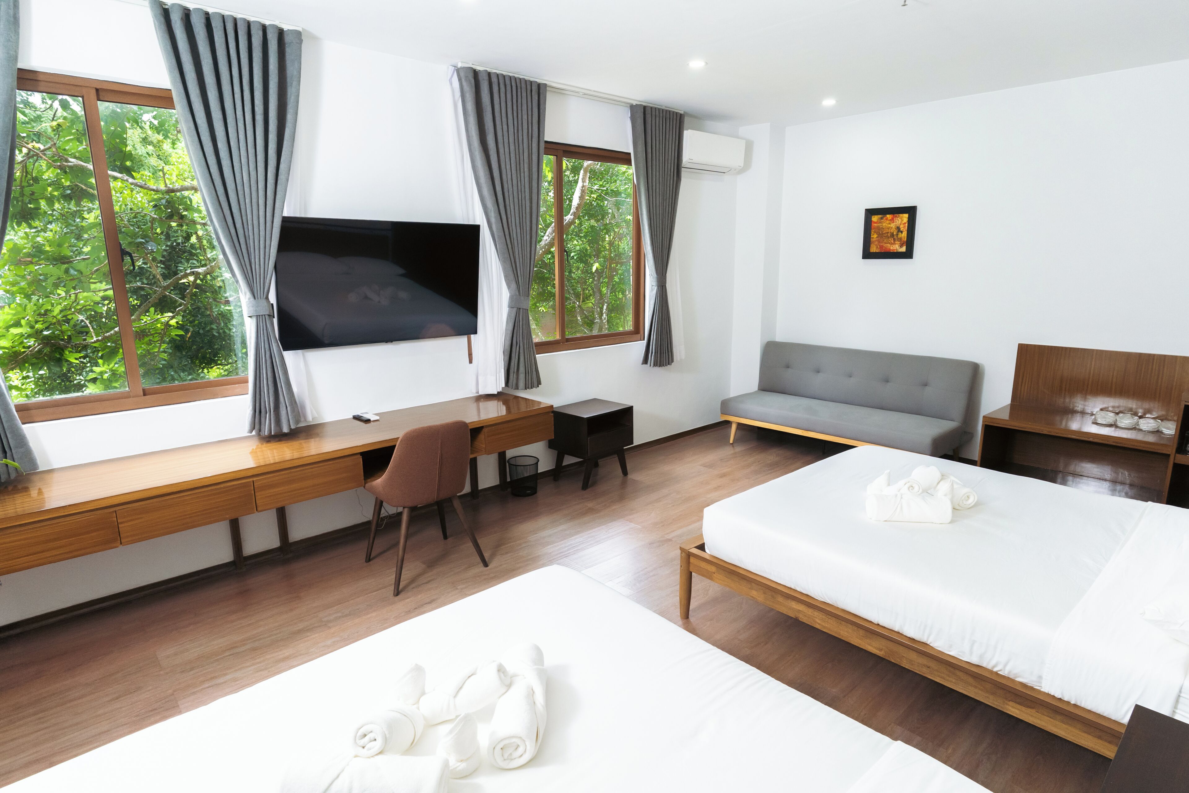 Habitación de hotel con cama, escritorio, silla, sofá y televisor.