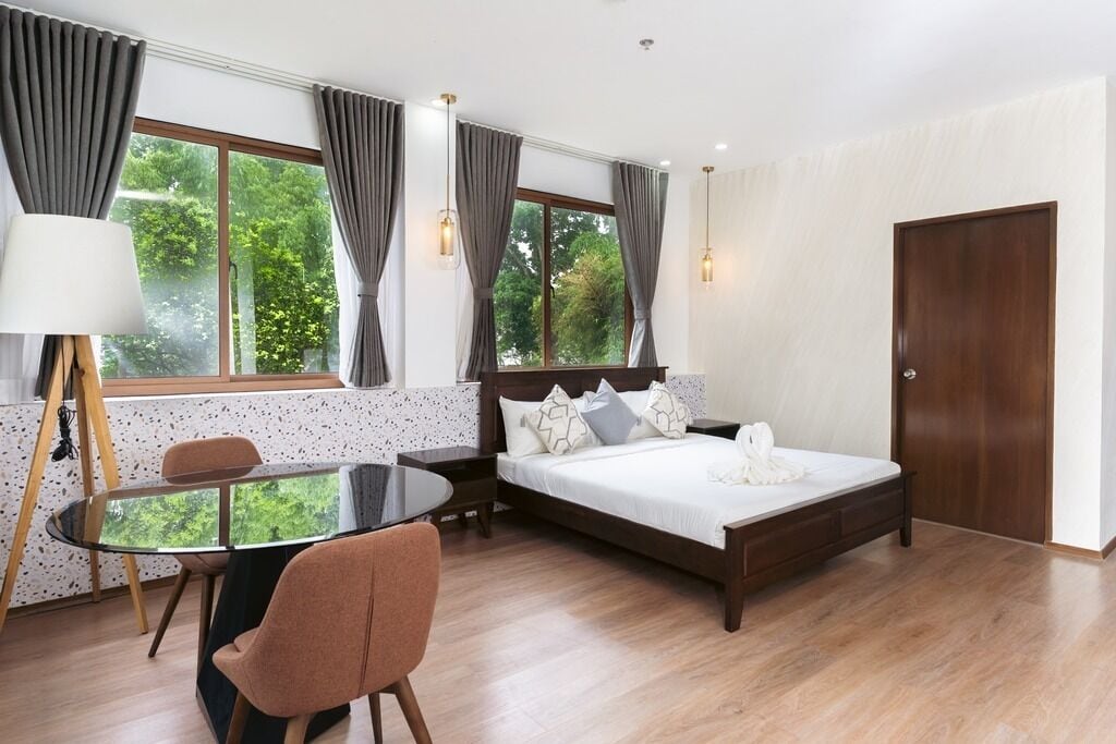 A bedroom with a bed, a table, chairs, and a window with curtains.