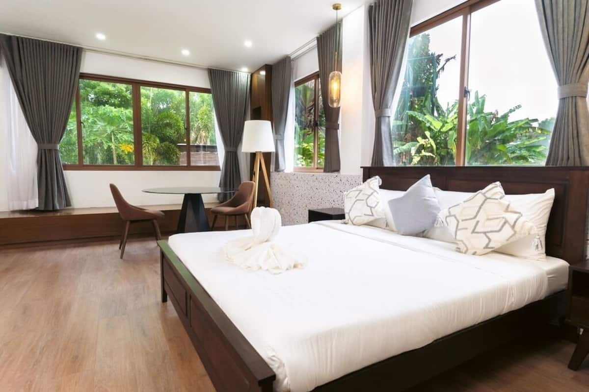 Un dormitorio con cama, una silla, una mesa y una ventana con cortinas.
