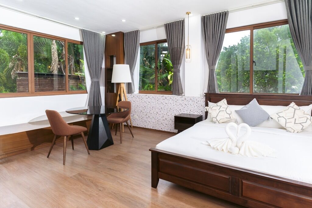 Une chambre à coucher avec un grand lit, un bureau, une chaise et une fenêtre avec des rideaux.