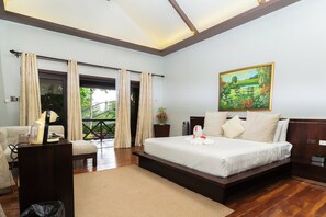 A hotel room with a large bed, a desk, a chair, and a balcony with curtains. - The Glens Tagaytay (Tagaytay)
