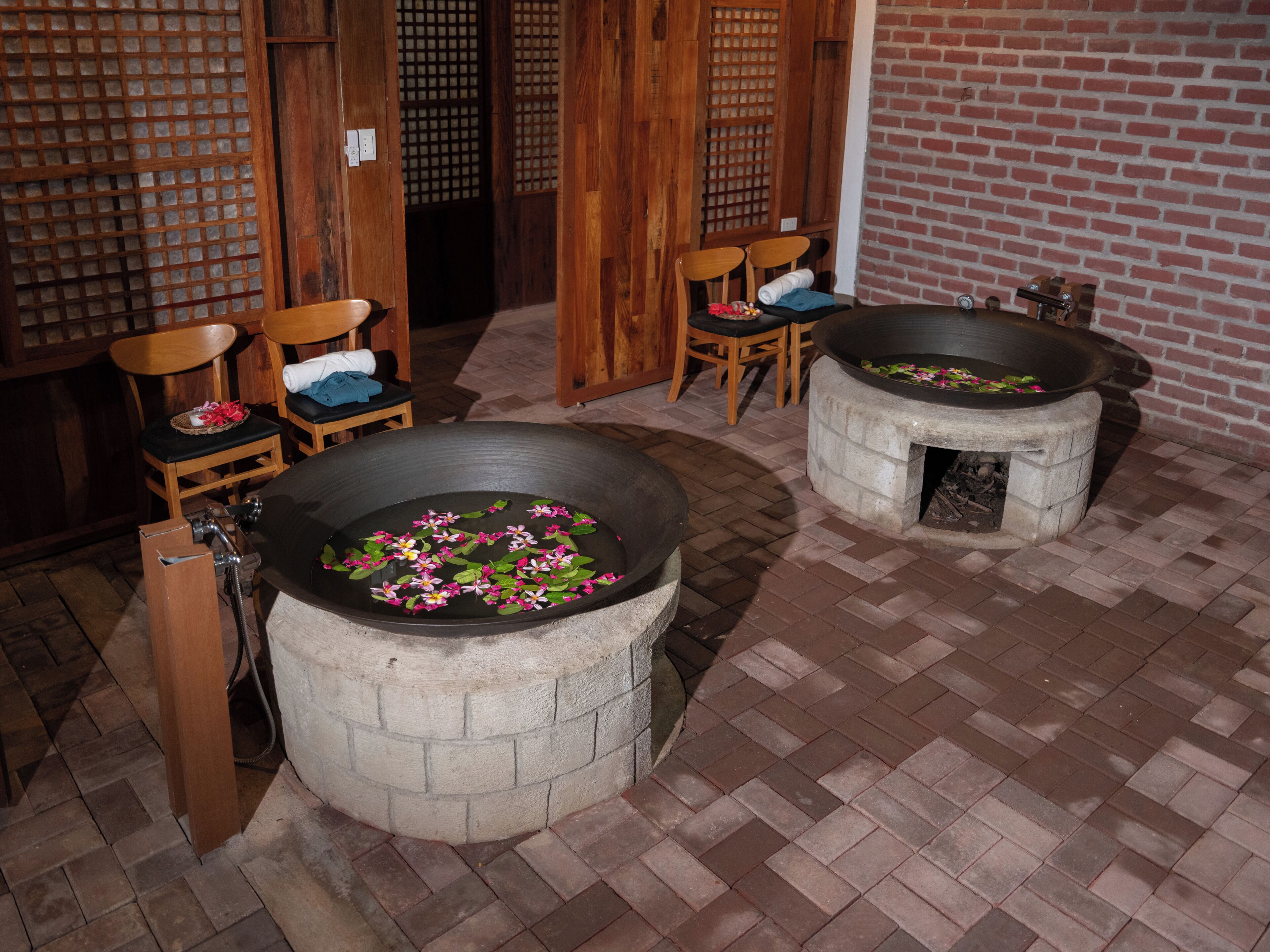 A traditional Japanese-style room with tatami flooring, wooden furniture, and a stone hot tub with flowers.