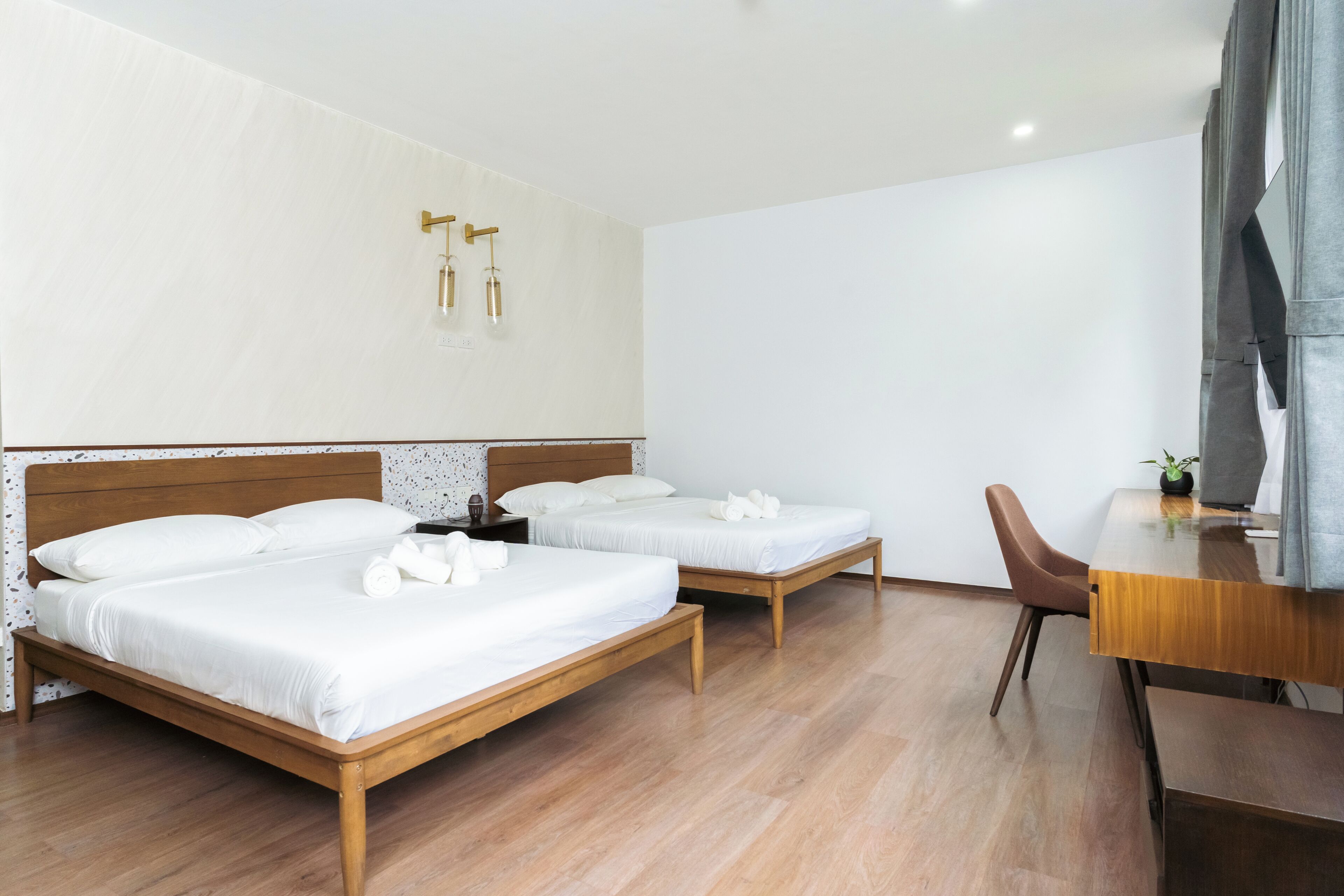 A hotel room with two single beds, a wooden desk, and a chair.