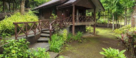 A wooden cabin with a porch and a wooden staircase leading to it.