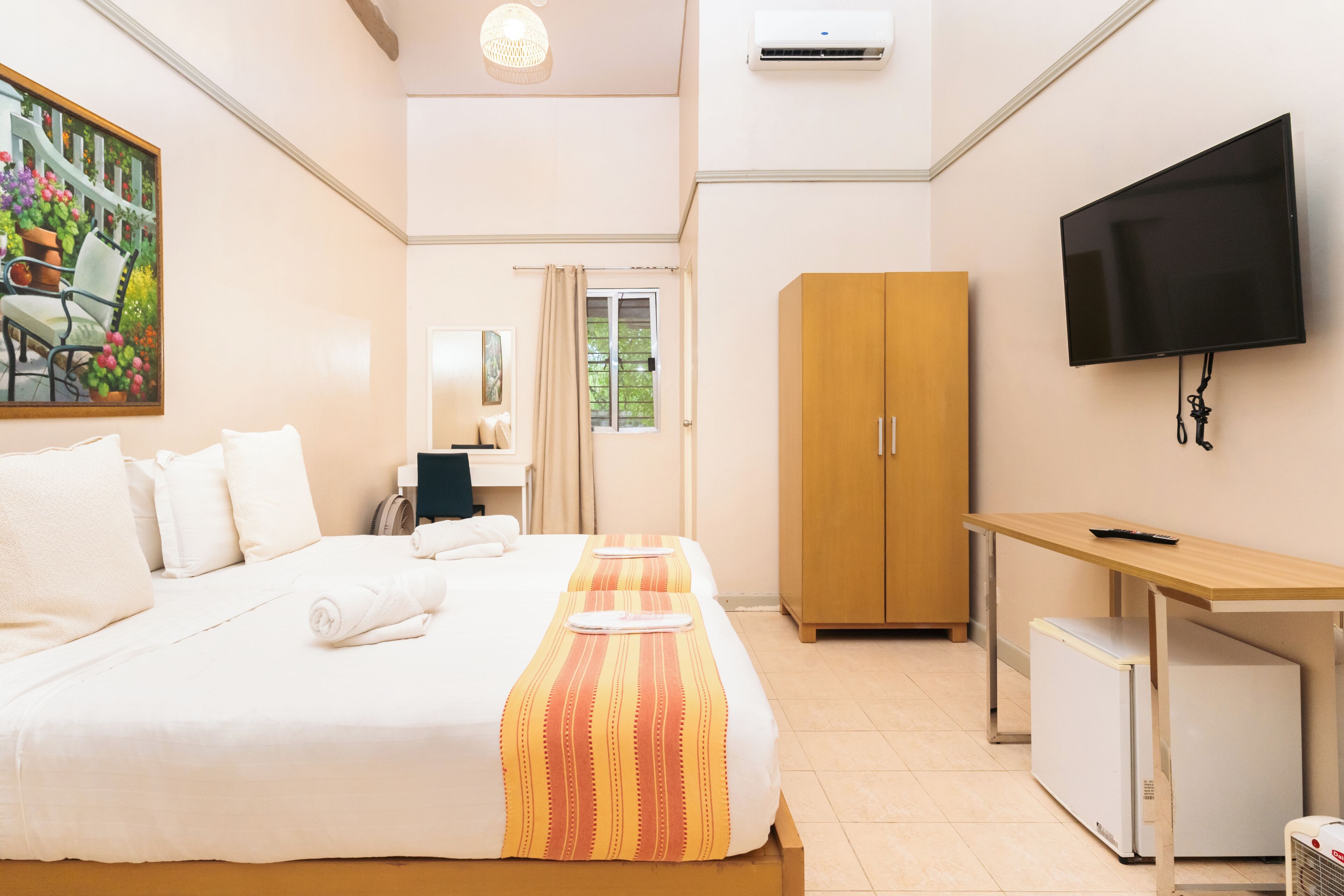 A hotel room with a bed, a desk, a television, and a wardrobe.