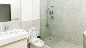 Un baño moderno con ducha acristalada, inodoro y lavamanos.