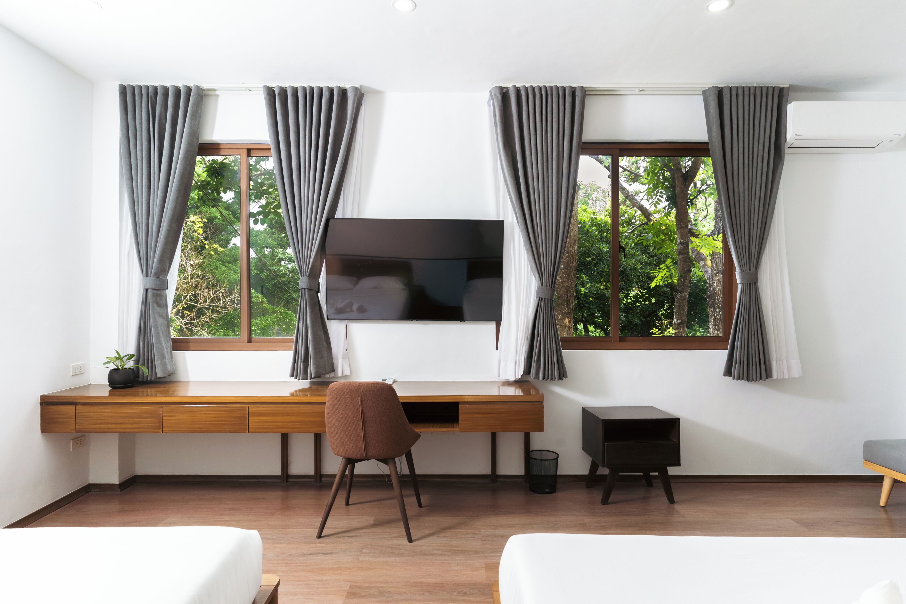 A modern room with a wooden desk, a TV, and a chair.