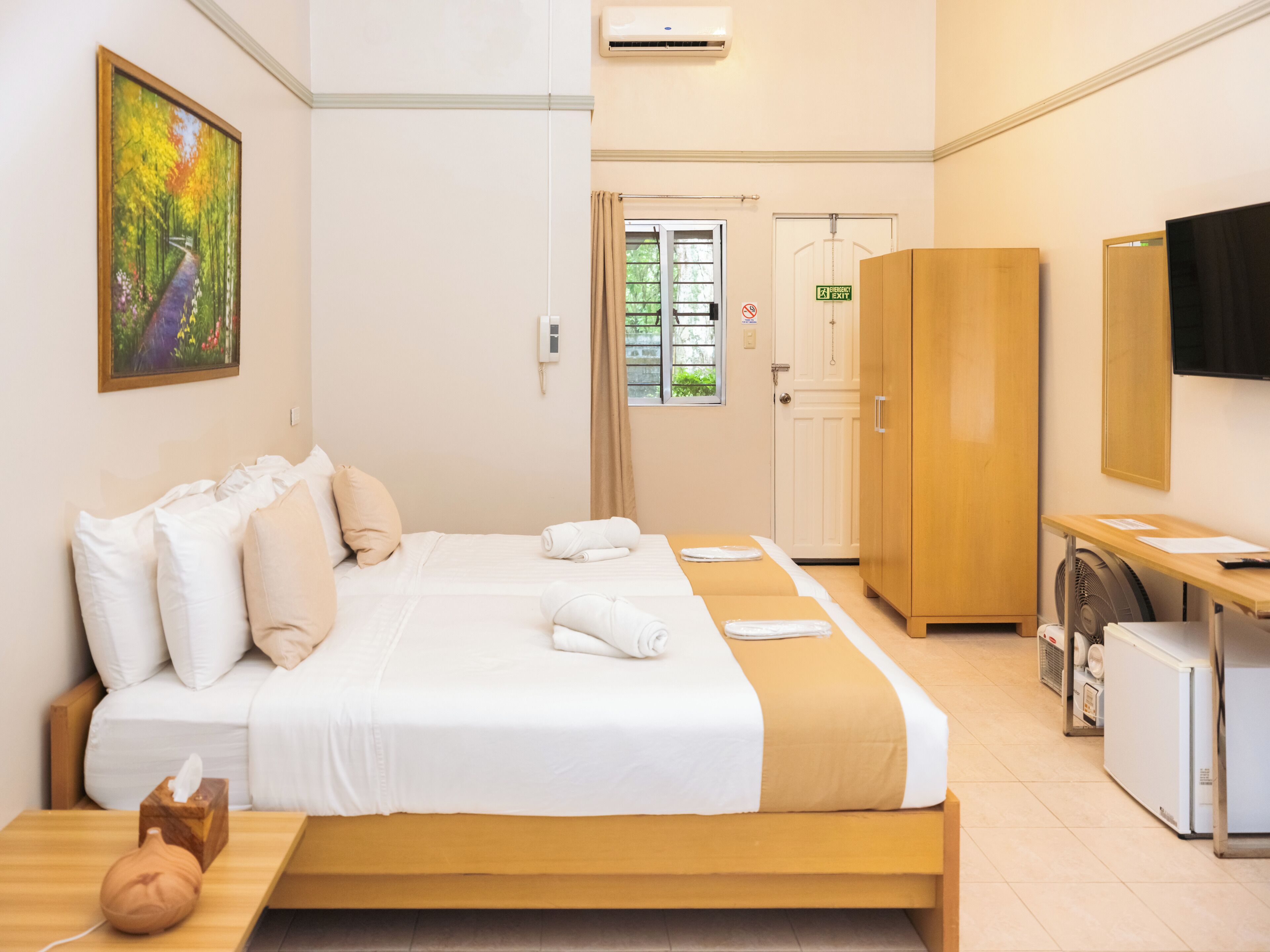 Een hotelkamer met een bed, een bureau, een kledingkast en een televisie.