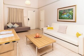 A living room with a sofa, a coffee table, a dining table, and a painting on the wall. - The Glens Tagaytay (Tagaytay)