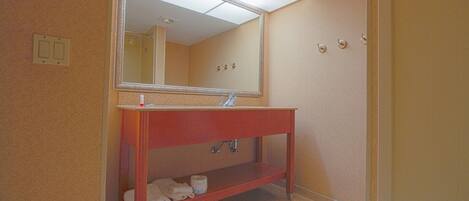 A bathroom with a wooden vanity, a mirror, a toilet, and a shower area.