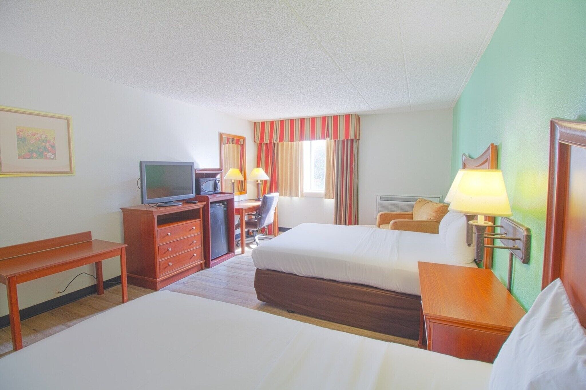 Une chambre d’hôtel avec deux lits, un bureau, une télévision et une lampe.