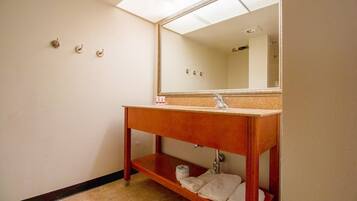 Une salle de bain avec un meuble-lavabo en bois, un miroir, un évier et une étagère avec des serviettes.