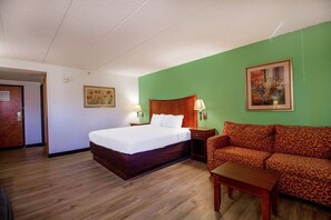 Una habitación de hotel con una cama, un sofá, una mesita y dos lámparas de pared.