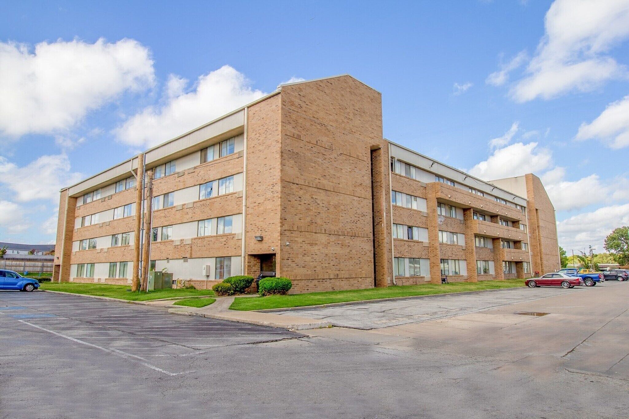 A multi-story building with a brick facade, large windows, and a parking lot.