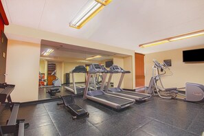 Un gimnasio con cintas de correr, una bicicleta estática y un espejo.