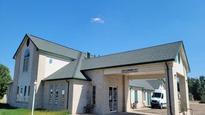 A two-story building with a covered parking area and a sign indicating 'LOW CLEARANCE 9'6' for vehicles.