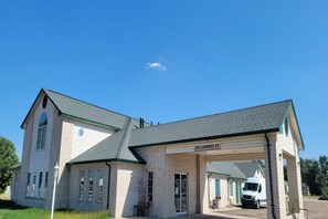 A two-story building with a covered parking area and a white van parked inside.