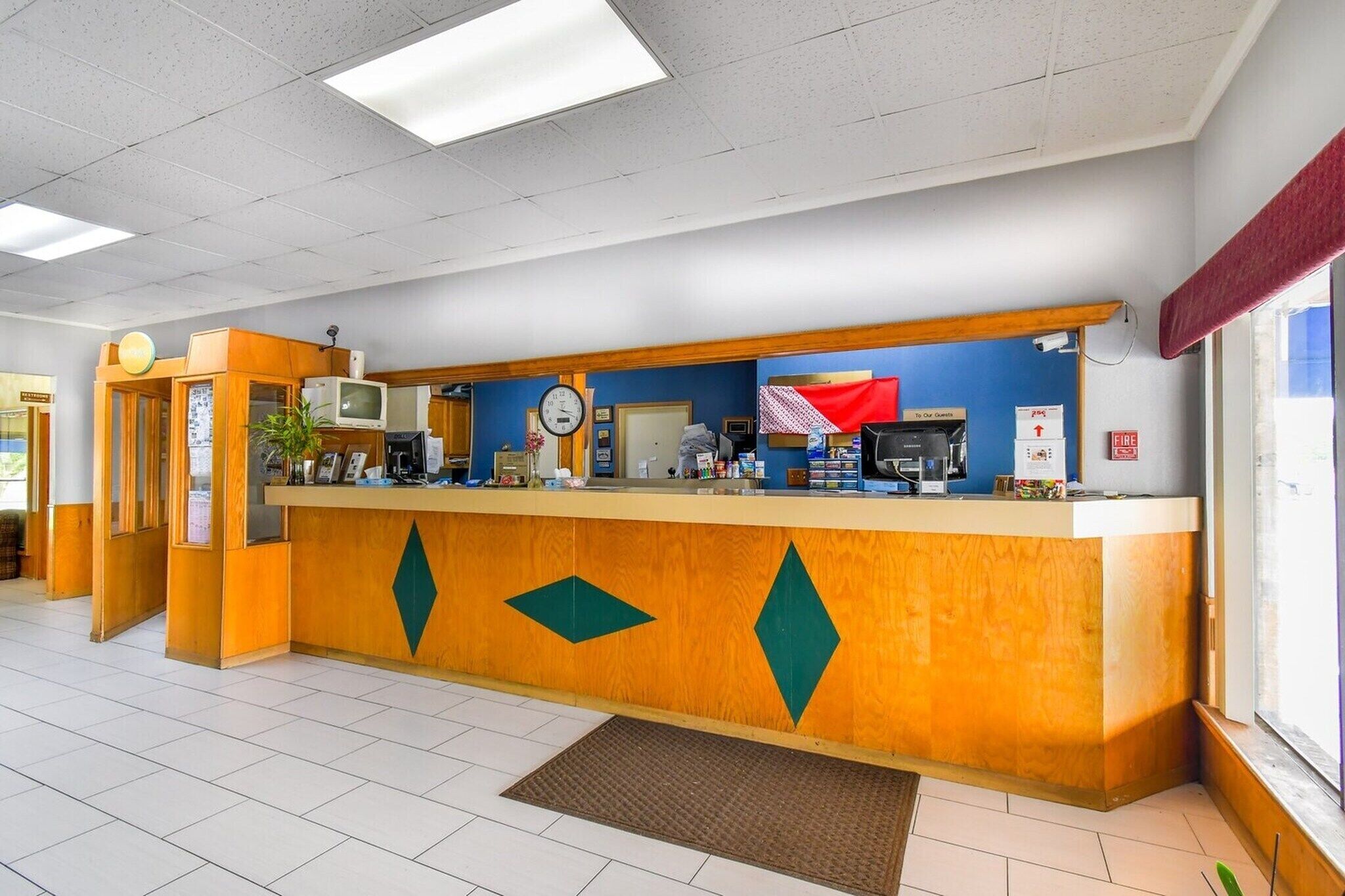 A reception desk with a clock, a television, and a fire alarm.