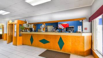 A reception desk with a clock, a television, and a fire alarm.