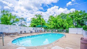 A swimming pool with lounge chairs, a covered seating area, and a fenced deck.