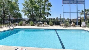 A clear blue pool with a 4 ft depth marker, surrounded by lounge chairs and a metal fence. - King Bed|Non Smoking (Valdosta GA)