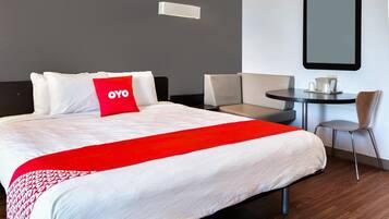 Et hotelværelse med en seng, en rød OYO pude, et rundt bord og en stol.