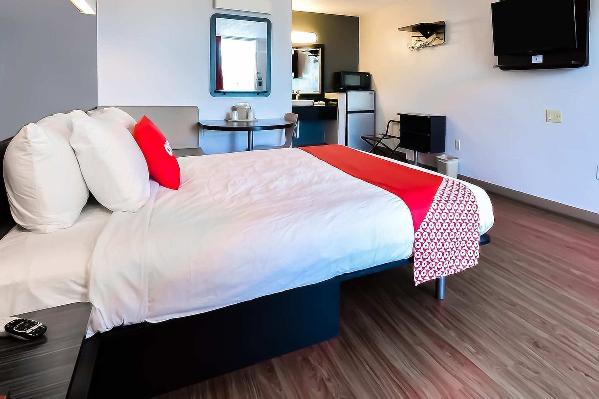 Une chambre d’hôtel équipée d’un lit, d’un bureau, d’une chaise, d’une télévision et d’une petite kitchenette.
