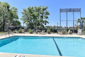 A clear blue pool with a 4 ft depth marker, surrounded by lounge chairs and a metal fence. - Premium King Bed|Nsmk (Valdosta GA)