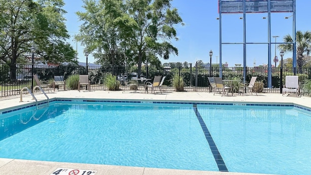 Piscina azul clara con indicador de profundidad de 1.2 metros, rodeada de sillas de descanso y una valla metálica.