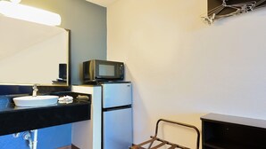 Une petite salle de bain comprenant un lavabo, un miroir, un four à micro-ondes et un petit réfrigérateur.