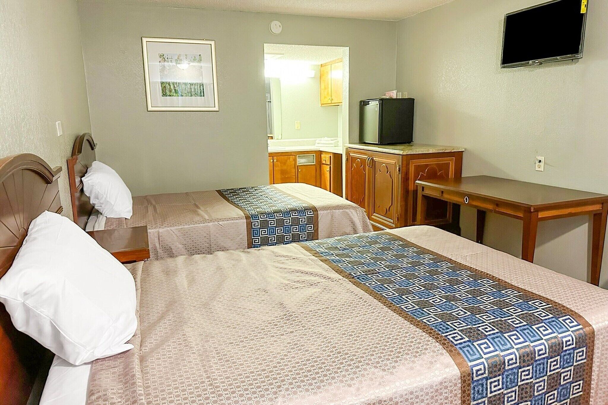 Une chambre d’hôtel avec deux lits, une télévision, un bureau et un miroir.