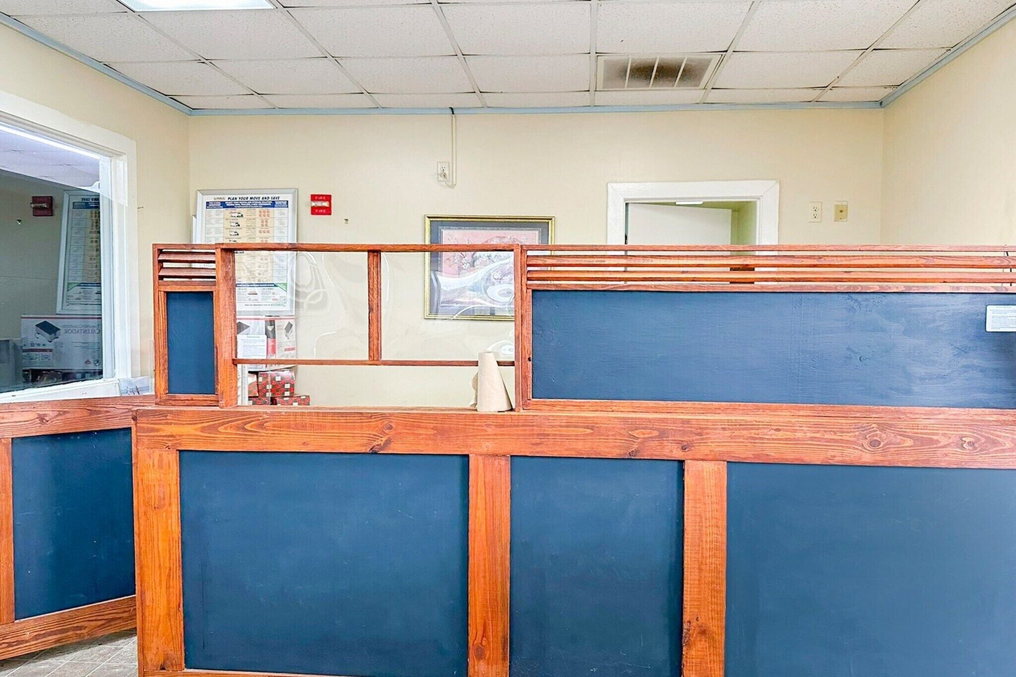 A reception area with a wooden reception desk, a bulletin board, and a door to the left.