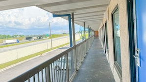 A covered balcony with a view of a highway and buildings in the distance. - 2 Full Beds Non-Smoking (Valdosta GA)