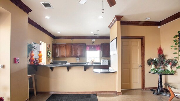A kitchen with wooden cabinets, a black countertop, and a black rug.