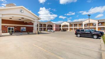 A hotel with a parking lot, multiple buildings, and a clear sky.