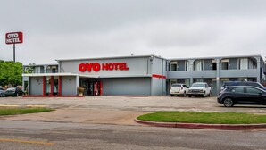 Un hotel con un llamativo letrero de 'OYO HOTEL', un estacionamiento y un edificio de varios pisos.