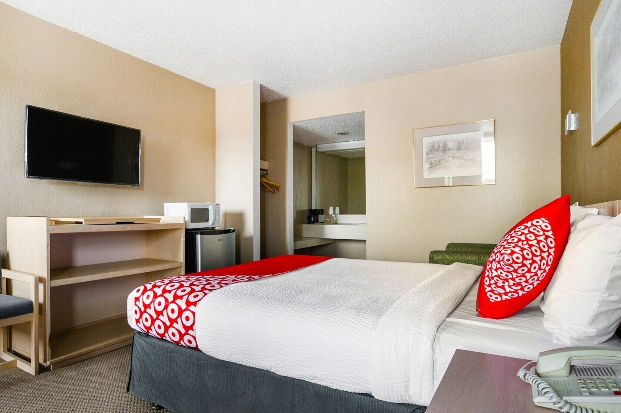 Une chambre d’hôtel équipée d’un lit, d’un bureau, d’une télévision, d’un miroir et d’un téléphone.