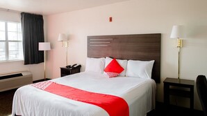 A hotel room with a large bed, bedside lamps, a telephone, and a window with curtains.