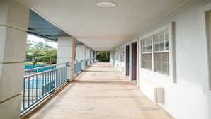 A covered corridor with a pool on one side, large windows on the other, and a flat ceiling.