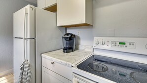 Een keuken met een koelkast, koffiezetapparaat, fornuis en kastjes.