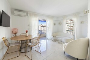 Ein modernes Wohnzimmer mit Essbereich, einer Couch und einem an der Wand befestigten Fernseher.